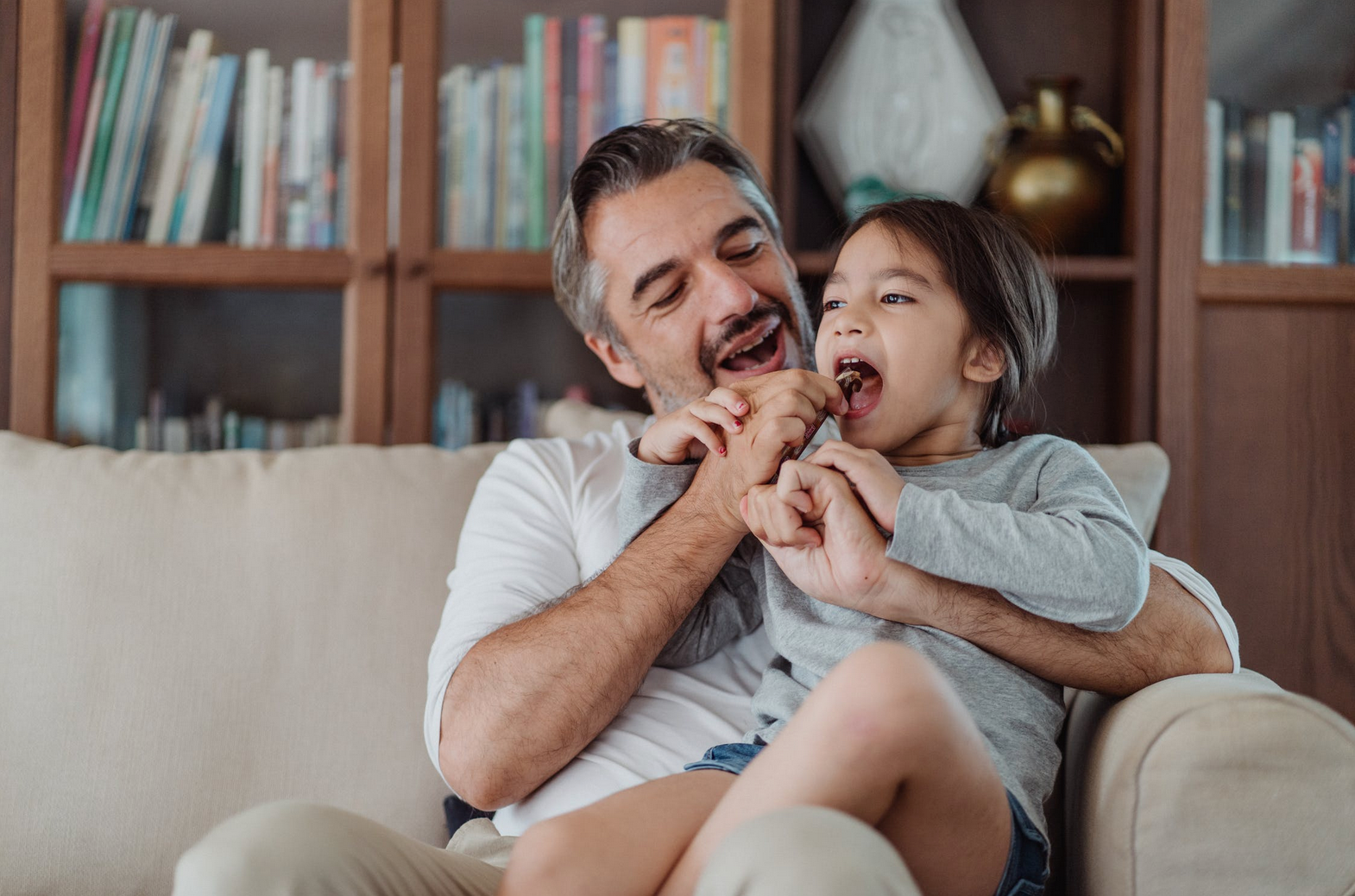 father and daughter eating chocolate on a couch