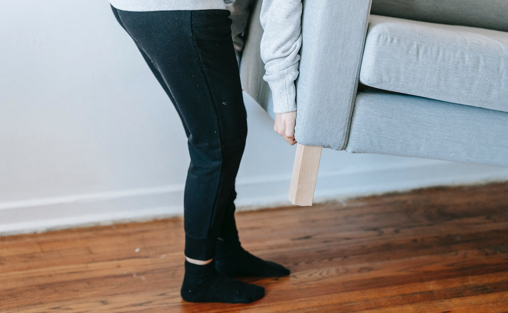 woman lifting heavy blue couch