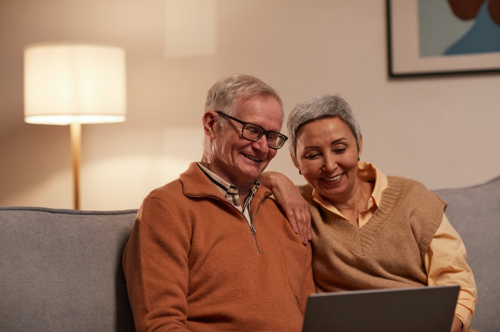 man and woman sitting on loveseat on computer