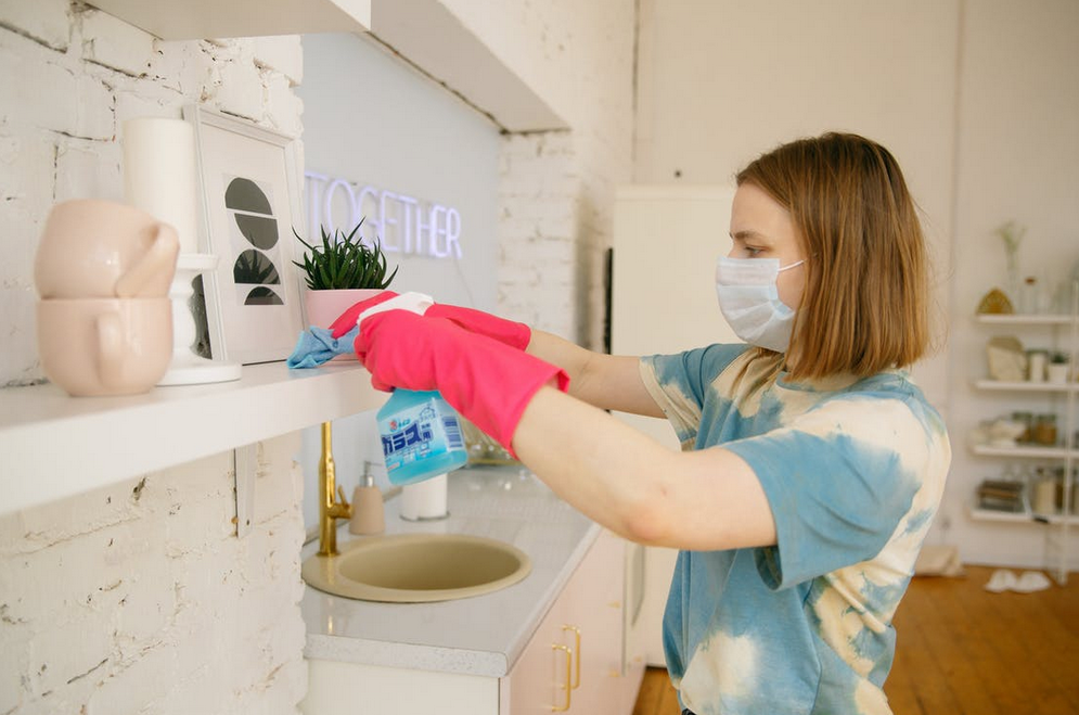woman cleaning furniture with mask and gloves on